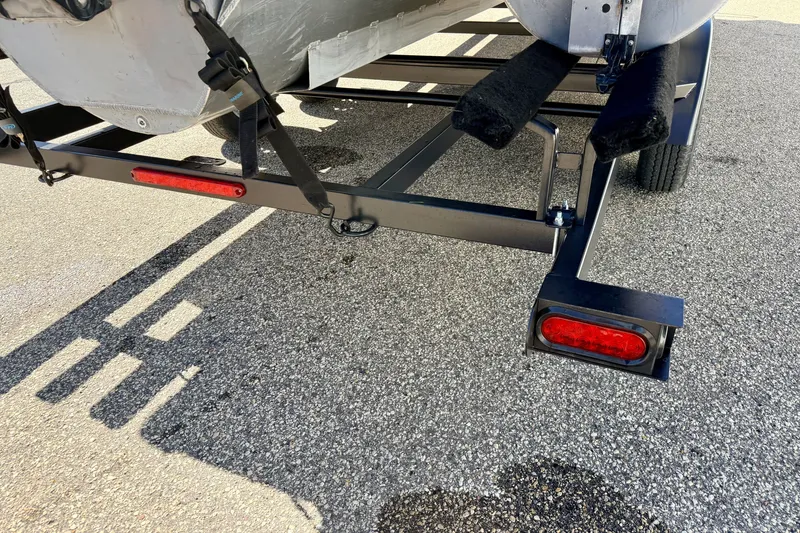 Slide: The Image of Trailer hitch and rear lights of a 2021 Manitou 23 Oasis boat on pavement. - 117