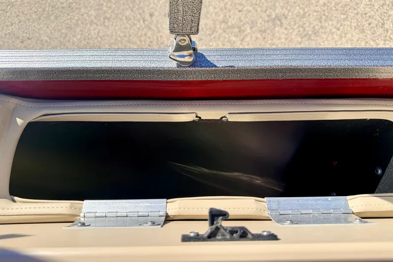 Slide: The Image of Open storage compartment on 2021 Manitou 23 Oasis boat, featuring metal hinges and latch. - 37