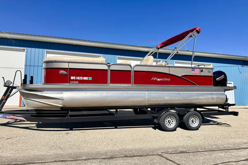Slide: The Image of 2021 Manitou 23 Oasis pontoon boat on trailer, red and silver design, parked outdoors. - 109