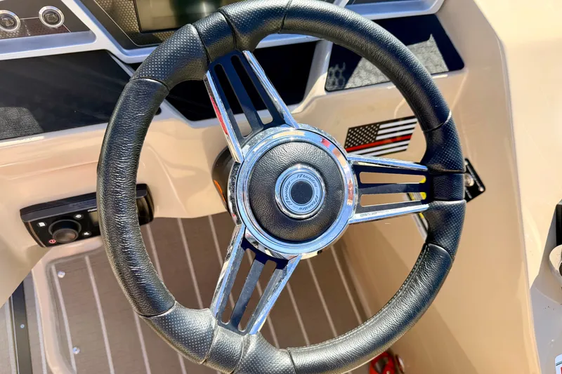 Slide: The Image of Steering wheel of 2021 Manitou 23 Oasis boat with sleek design and controls. - 54