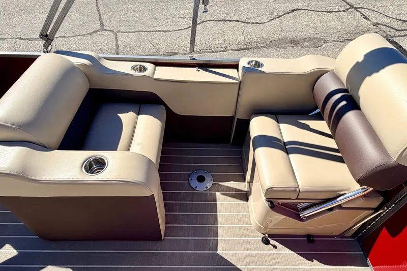Slide: The Image of 2021 Manitou 23 Oasis boat interior with beige seating and cup holders. - 35