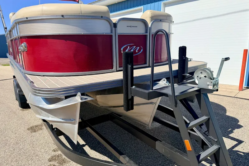 Slide: The Image of 2021 Manitou 23 Oasis pontoon boat on trailer, featuring red exterior and beige seating. - 104