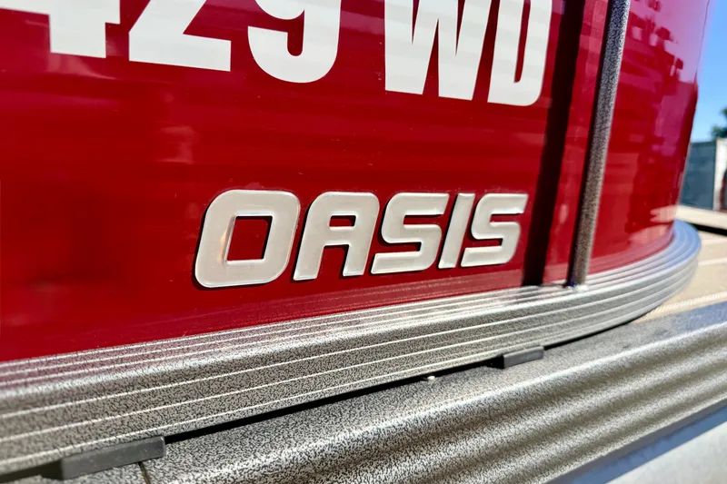 Slide: The Image of Close-up of 2021 Manitou 23 Oasis boat nameplate on red background. - 22