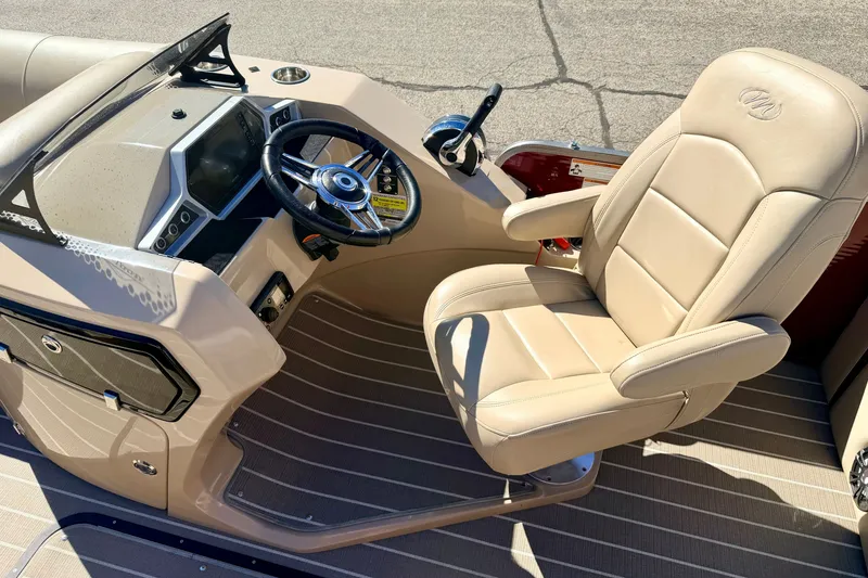 Slide: The Image of 2021 Manitou 23 Oasis boat cockpit with beige captain's chair and modern dashboard. - 44