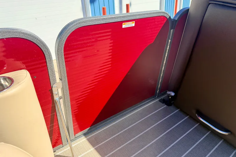 Slide: The Image of Interior view of a 2021 Manitou 23 Oasis boat with red paneling and beige seating. - 62
