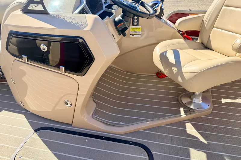 Slide: The Image of 2021 Manitou 23 Oasis boat interior with beige captain's chair and steering console. - 80