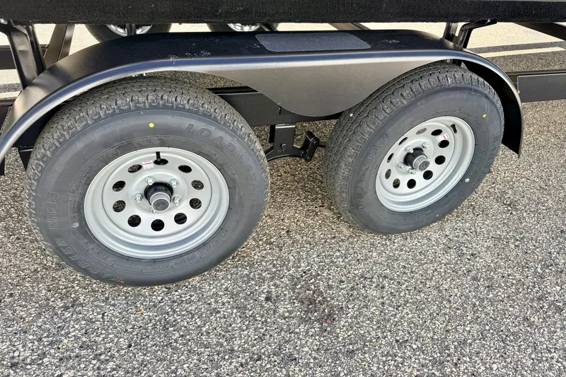 Slide: The Image of Dual wheels of a 2021 Manitou 23 Oasis trailer on asphalt surface. - 97