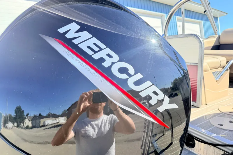 Slide: The Image of Mercury FourStroke engine on 2021 Manitou 23 Oasis boat, reflecting surroundings. - 25