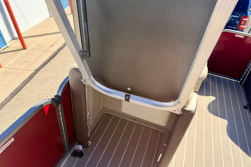 Slide: The Image of 2021 Manitou 23 Oasis boat interior with open storage compartment and striped flooring. - 65