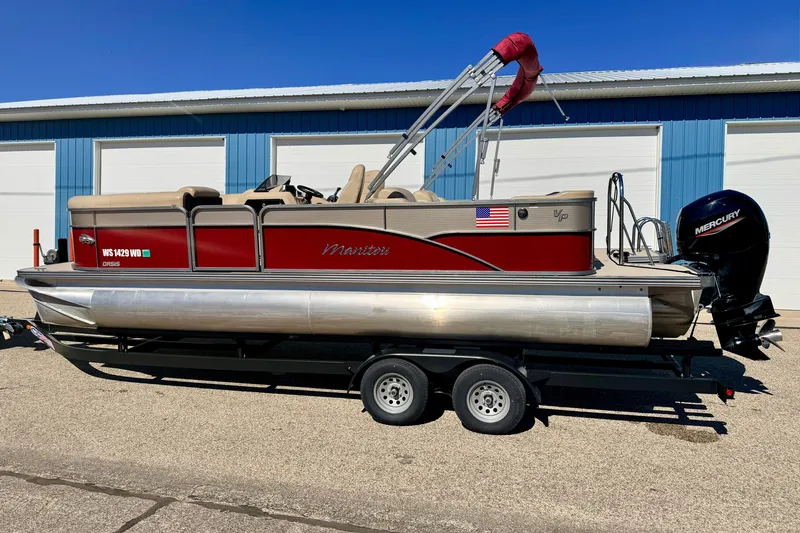 Slide: The Image of 2021 Manitou 23 Oasis pontoon boat with Mercury engine on trailer, parked outdoors. - 5