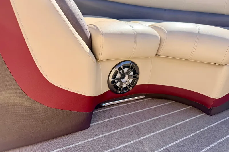 Slide: The Image of 2021 Manitou 23 Oasis boat interior with beige and red seating, featuring a built-in speaker. - 87