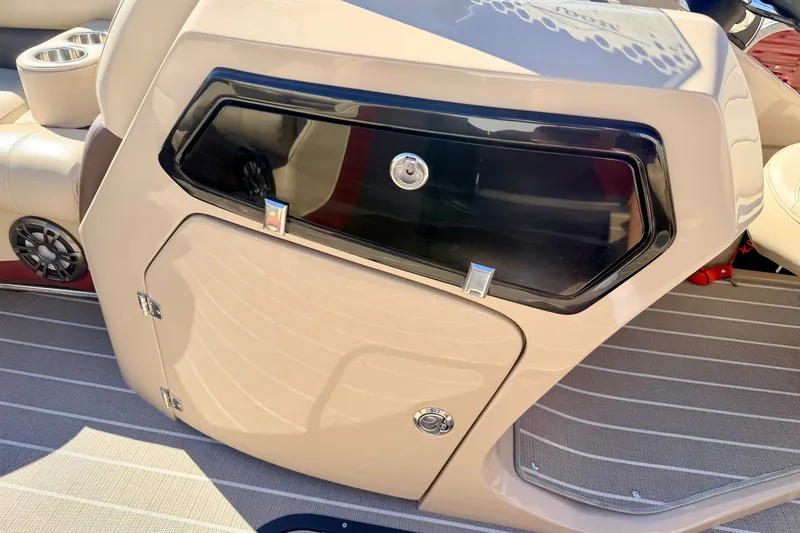 Slide: The Image of 2021 Manitou 23 Oasis boat interior with storage compartment and cup holders. - 55