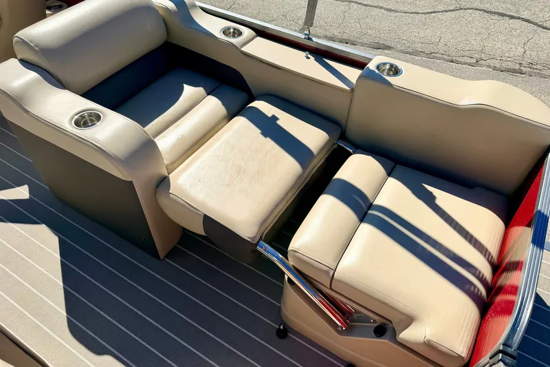 Slide: The Image of 2021 Manitou 23 Oasis boat interior with beige seating and cup holders. - 31