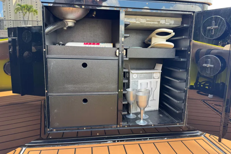 Slide: The Image of Open storage cabinet on a 2016 Midnight Express 43 Open boat, featuring wine glasses and accessories. - 18