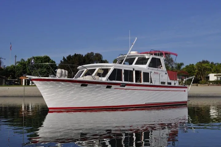 Slide: The Image of 1983 Roughwater 41 boat on calm water, featuring a sleek white and red design. - 41