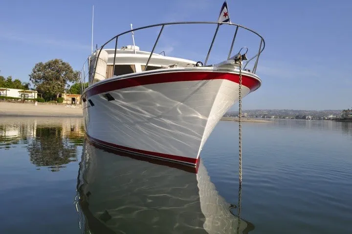 Slide: The Image of 1983 Roughwater 41 boat anchored on calm water, reflecting clear blue sky. - 42