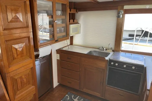 Slide: The Image of 1983 Roughwater 41 boat kitchen with wooden cabinets, stove, sink, and window view. - 14