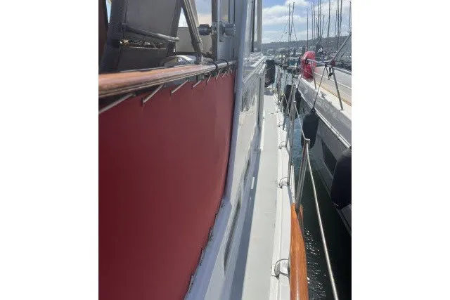 Slide: The Image of 1983 Roughwater 41 yacht docked at marina, side view with red paneling. - 32