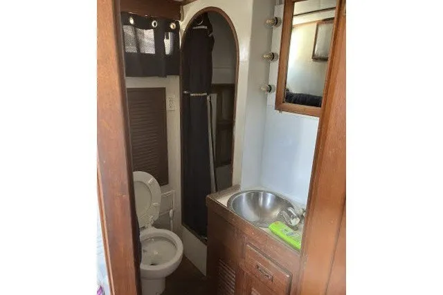 Slide: The Image of 1983 Roughwater 41 boat bathroom with sink, toilet, and shower curtain. - 23