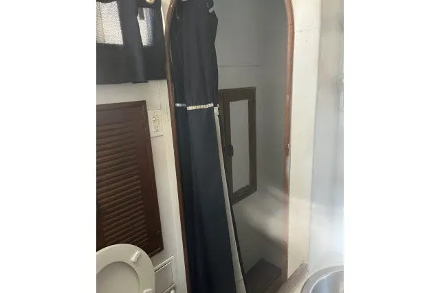 Slide: The Image of Interior of 1983 Roughwater 41 boat featuring a compact bathroom with shower curtain. - 24