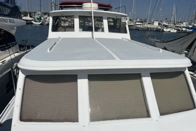 Slide: The Image of 1983 Roughwater 41 boat docked in a marina, showcasing its sleek design and spacious deck. - 34