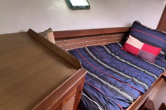 Slide: The Image of Cozy cabin interior of 1983 Roughwater 41 boat with striped bedding and wooden accents. - 19