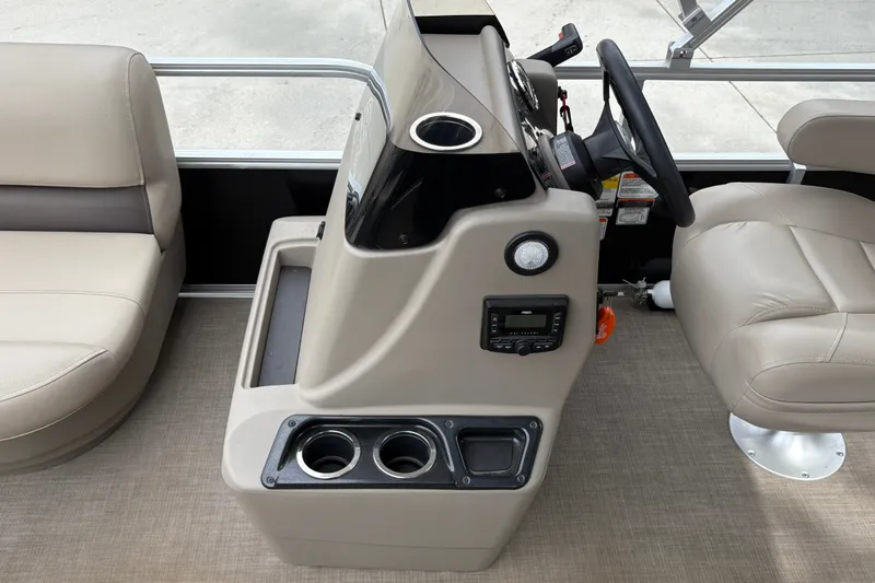 Slide: The Image of 2025 Sun Tracker Party Barge 16 DLX helm with beige seating and control panel. - 18