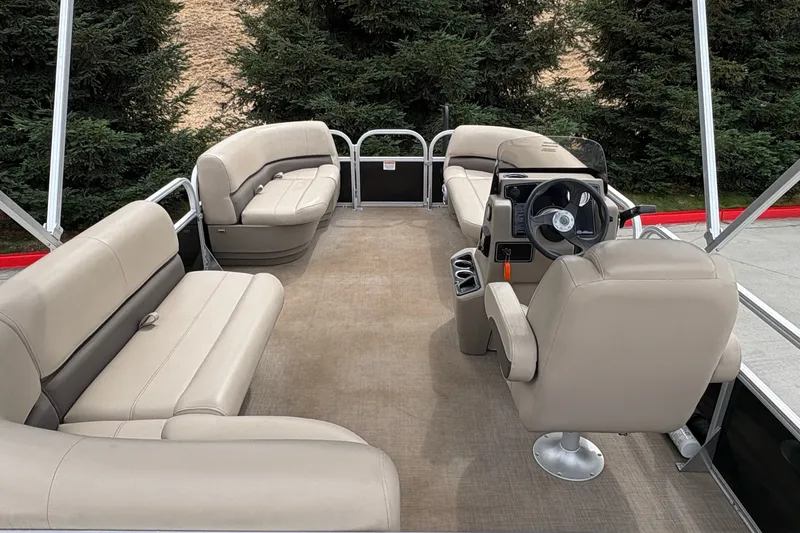 Slide: The Image of 2025 Sun Tracker Party Barge 16 DLX interior with beige seating and steering console. - 15