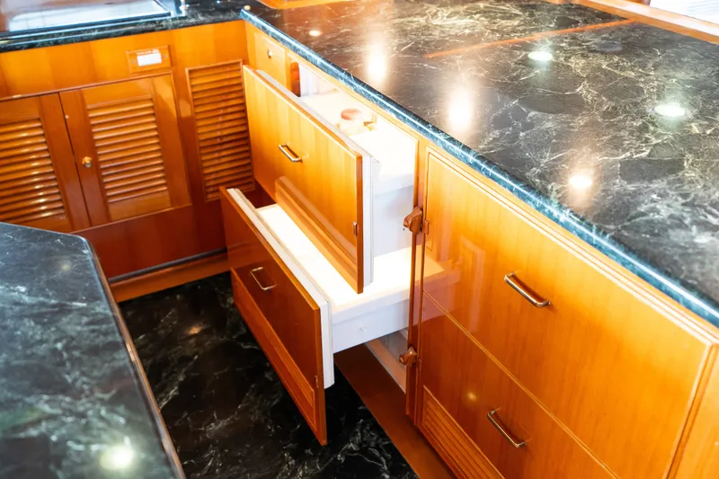 Slide: The Image of Luxurious Marlow 61C 2009 yacht kitchen with open wooden drawers and marble countertop. - 58
