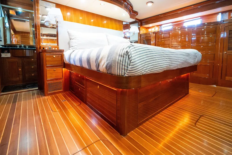 Slide: The Image of Luxurious Marlow 61C yacht bedroom with wooden interiors, striped bedding, and ambient lighting. - 120