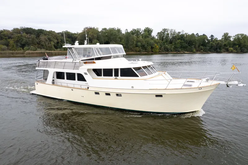 Slide: The Image of 2009 Marlow 61C yacht cruising on a calm river with lush green trees in the background. - 3