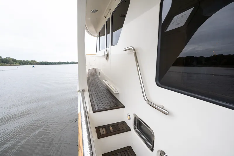 Slide: The Image of Side view of 2009 Marlow 61C yacht with wooden steps and railing by the water. - 17