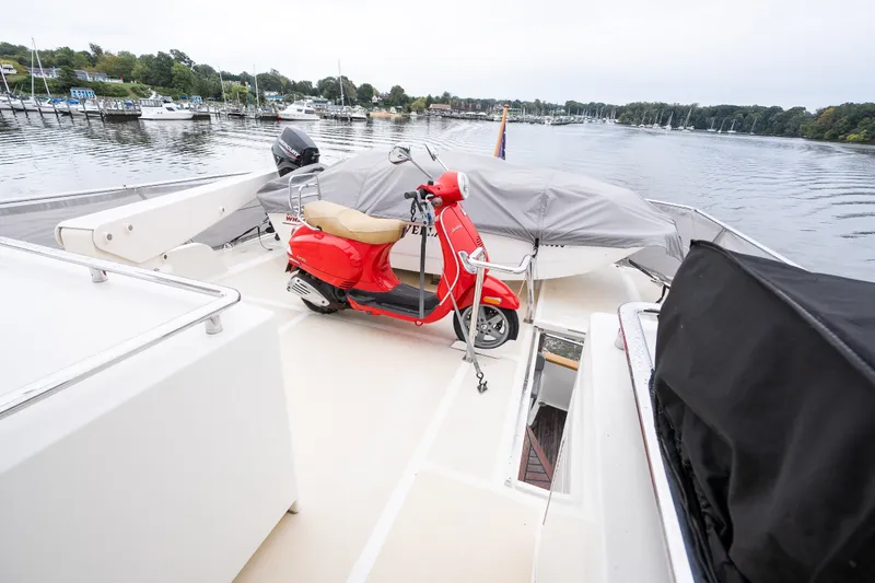 Slide: The Image of Red scooter on 2009 Marlow 61C yacht deck, docked by a serene marina. - 77