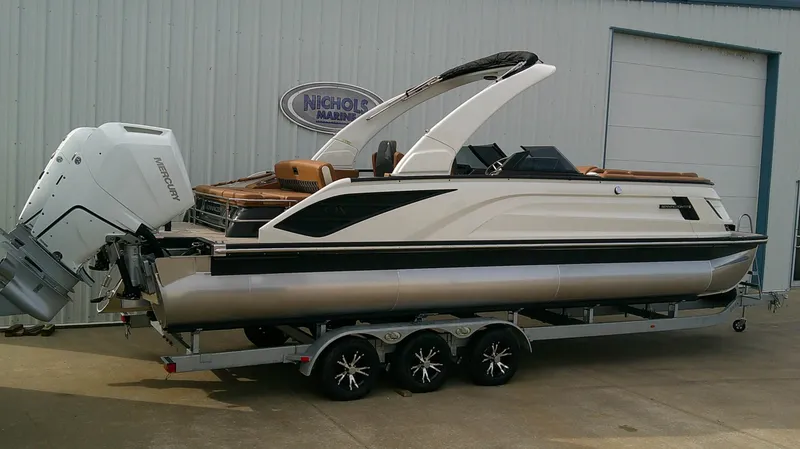 Slide: The Image of A sleek 2027 Bennington 27 QXSBA pontoon boat on a trailer in front of a building. - 4