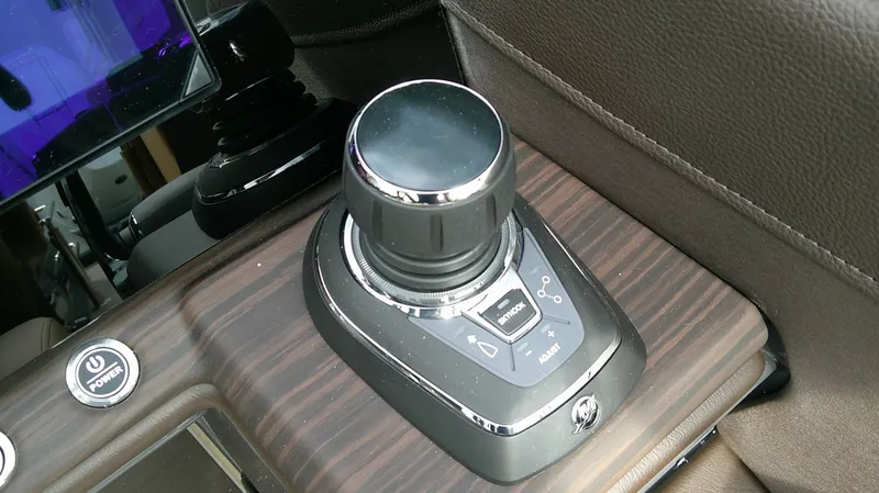 Slide: The Image of Close-up of a modern boat control system with a sleek joystick and wood paneling. - 12