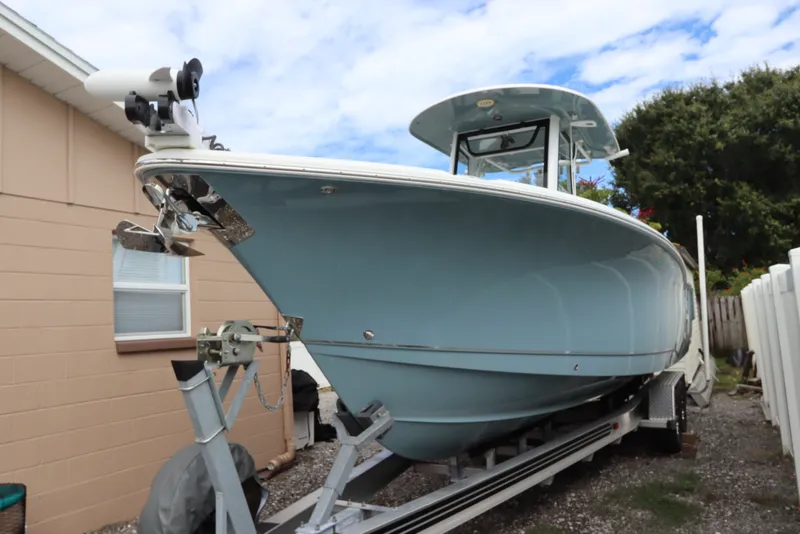 Slide: The Image of 2021 Sea Hunt Ultra 275SE boat on trailer, light blue hull, parked outdoors. - 1
