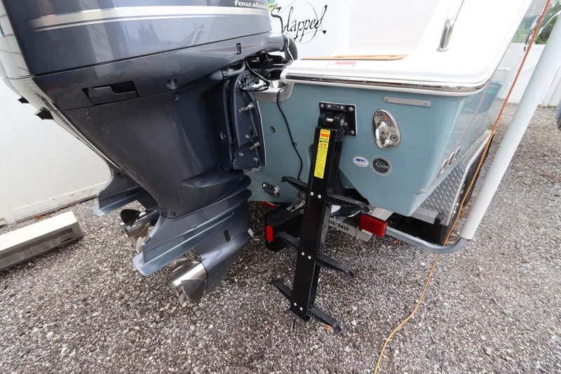 Slide: The Image of 2021 Sea Hunt Ultra 275SE boat with dual outboard motors and a ladder on gravel. - 6