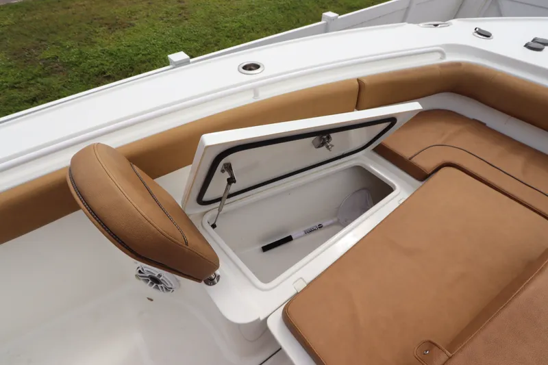 Slide: The Image of 2021 Sea Hunt Ultra 275SE boat interior with open storage compartment and tan seating. - 28