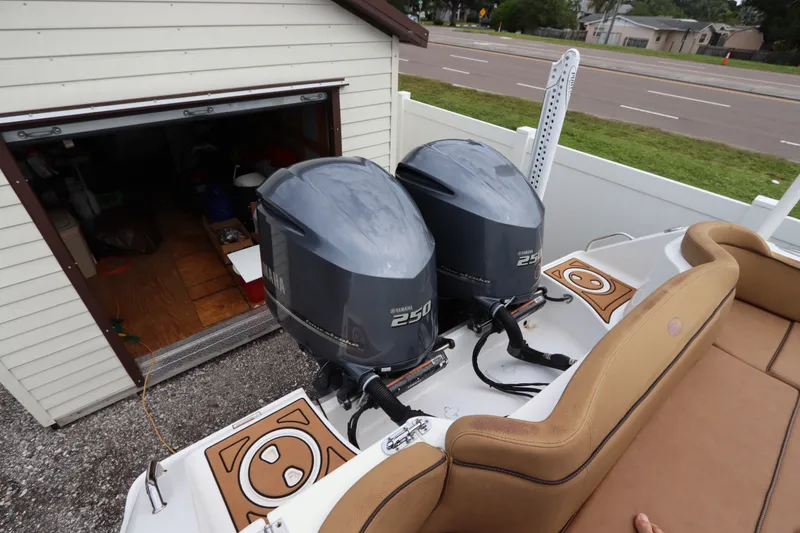 Slide: The Image of 2021 Sea Hunt Ultra 275SE boat with twin Yamaha 250 engines, parked near a garage. - 7