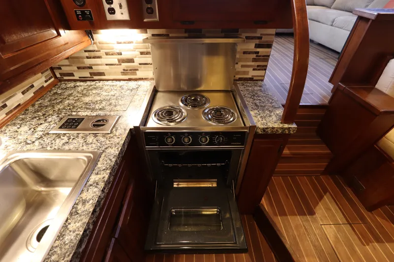 Slide: The Image of 1985 Viking 50 Cockpit Motor Yacht kitchen with stove, granite countertops, and wooden flooring. - 35