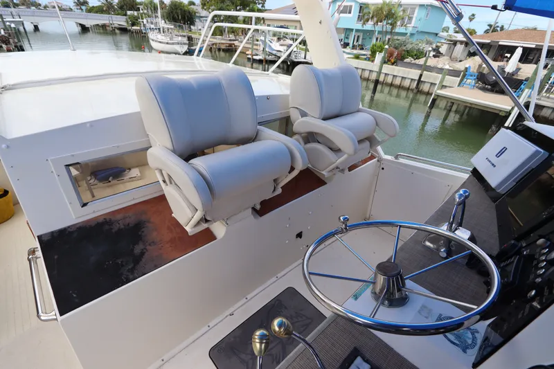 Slide: The Image of 1985 Viking 50 Cockpit Motor Yacht helm with dual captain chairs and steering wheel. - 17