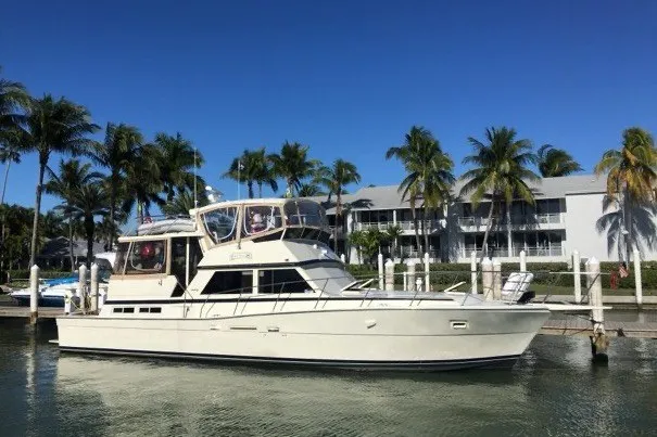 Slide: The Image of 1985 Viking 50 Cockpit Motor Yacht docked near palm trees and waterfront buildings. - 1