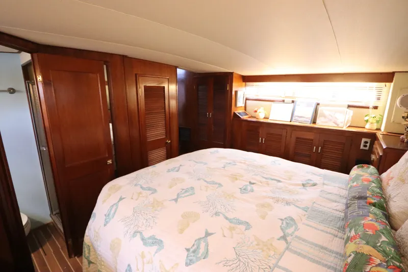 Slide: The Image of Cozy bedroom interior of 1985 Viking 50 Cockpit Motor Yacht with wooden cabinetry and nautical bedding. - 47