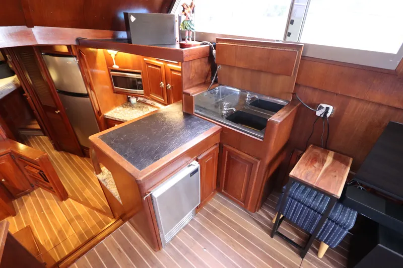 Slide: The Image of 1985 Viking 50 Cockpit Motor Yacht kitchen with wood cabinetry, stainless appliances, and dual sink. - 25