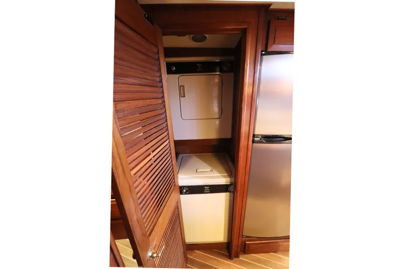 Slide: The Image of Laundry area inside 1985 Viking 50 Cockpit Motor Yacht with wooden cabinetry and appliances. - 37