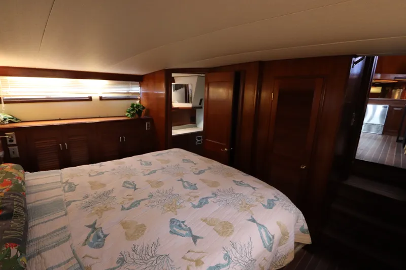 Slide: The Image of Cozy bedroom in 1985 Viking 50 Cockpit Motor Yacht with wooden cabinetry and nautical-themed bedding. - 49