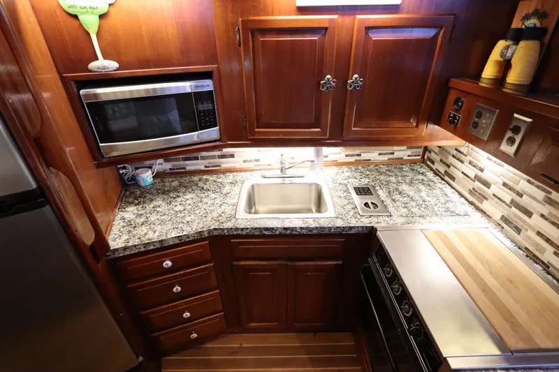 Slide: The Image of Luxurious 1985 Viking 50 Cockpit Motor Yacht kitchen with granite countertops and wooden cabinetry. - 31