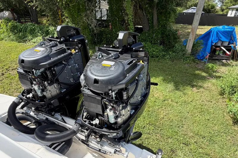Slide: The Image of Twin outboard engines on a 2003 Stamas 290 Express boat, parked on grassy area. - 38