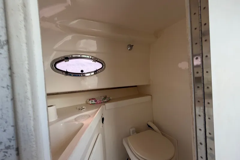 Slide: The Image of 2003 Stamas 290 Express boat bathroom with sink, toilet, and porthole window. - 26