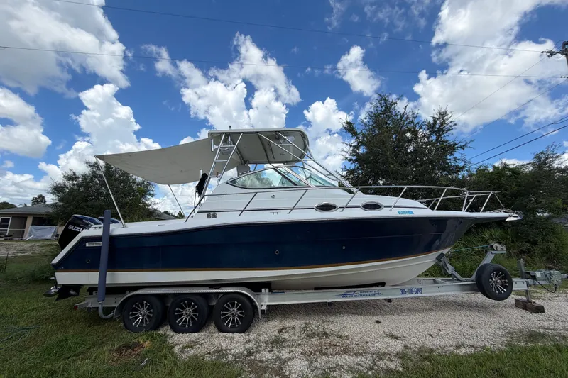 The Image of 2003 Stamas 290 Express boat on trailer under blue sky with clouds. - 0